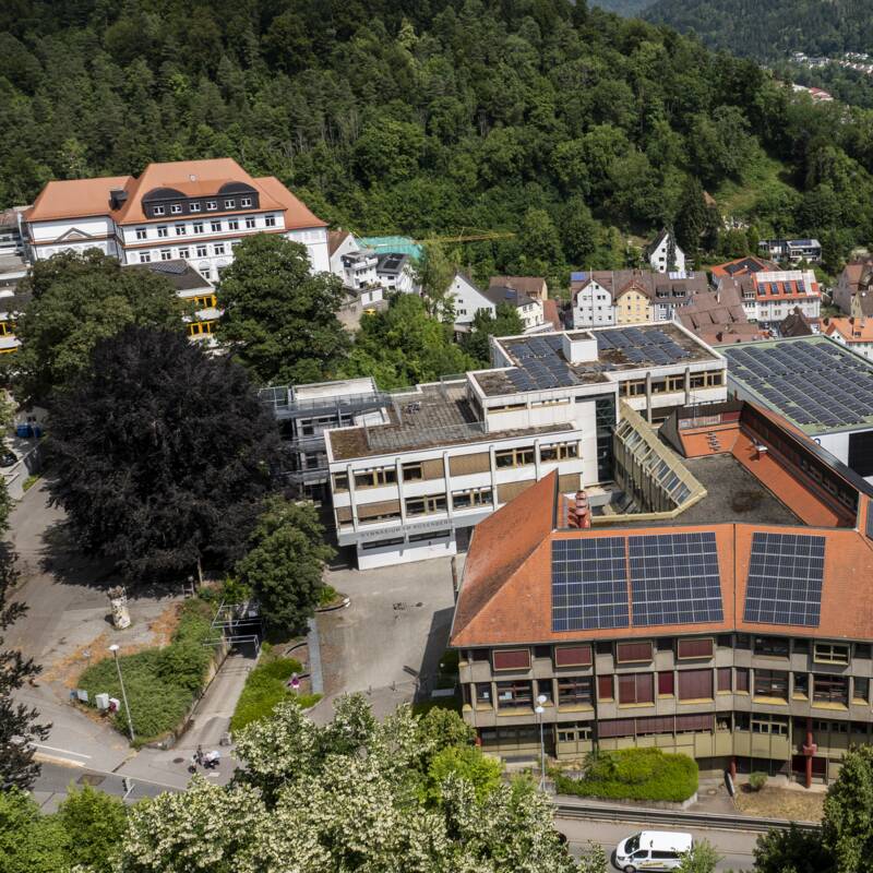 Eine Stadtansicht von oben zeigt das Gymnasium am Rosenberg inmitten der Stadt Oberndorf, umgeben von üppigen grünen Wäldern und sanften Hügeln.