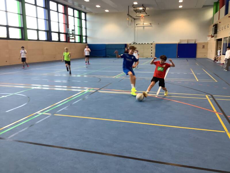 Schüler spielen Fußball in der Sporthalle.
