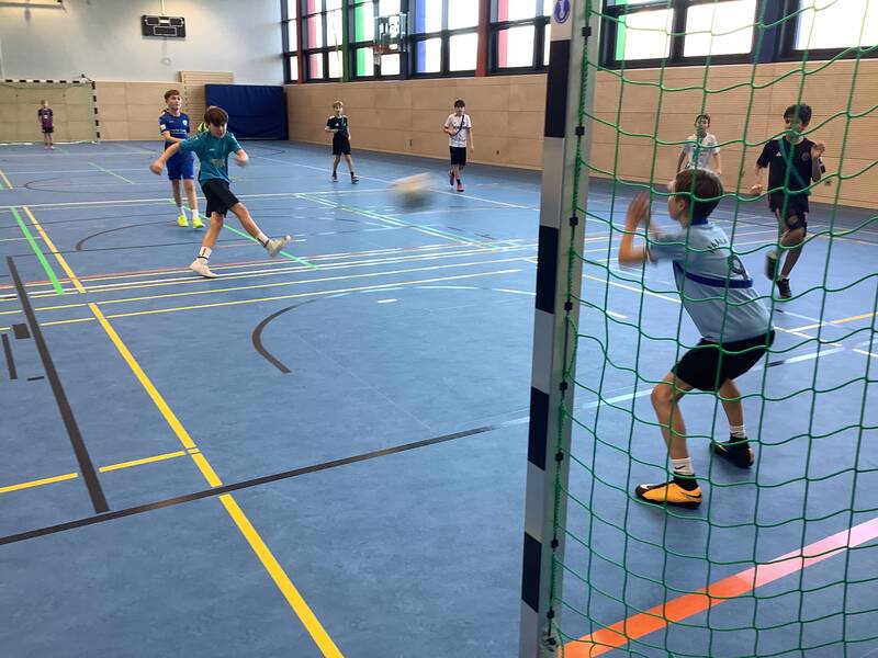 Schüler spielen Fußball in der Sporthalle.