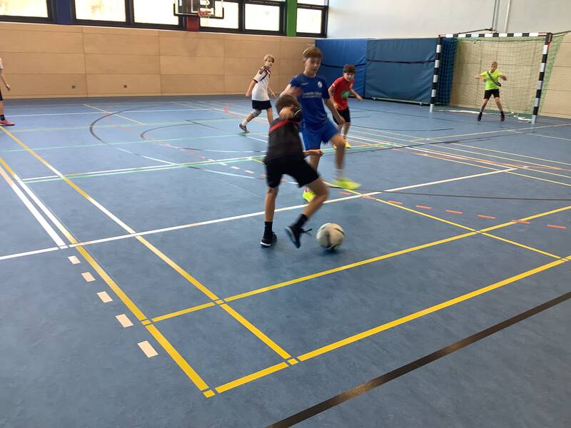 Schüler spielen Fußball in der Sporthalle.
