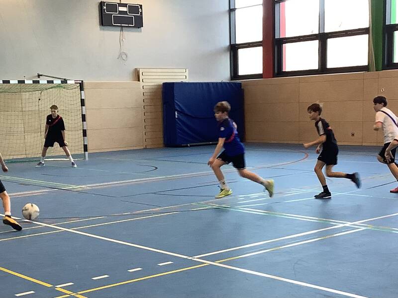 Schüler spielen Fußball in der Sporthalle.