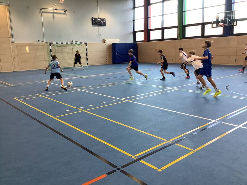 Schüler spielen Fußball in der Sporthalle.
