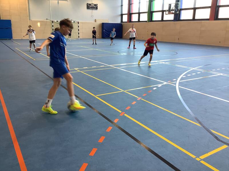 Schüler spielen Fußball in der Sporthalle.