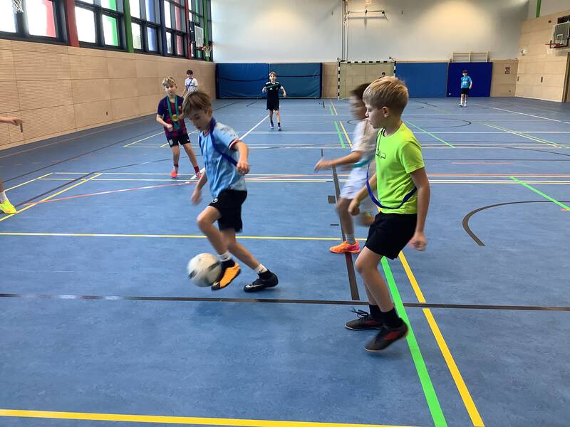 Schüler spielen Fußball in der Sporthalle.