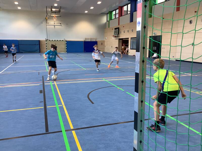 Schüler spielen Fußball in der Sporthalle.