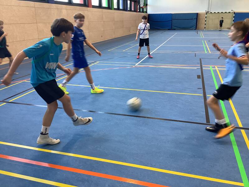 Schüler spielen Fußball in der Sporthalle.