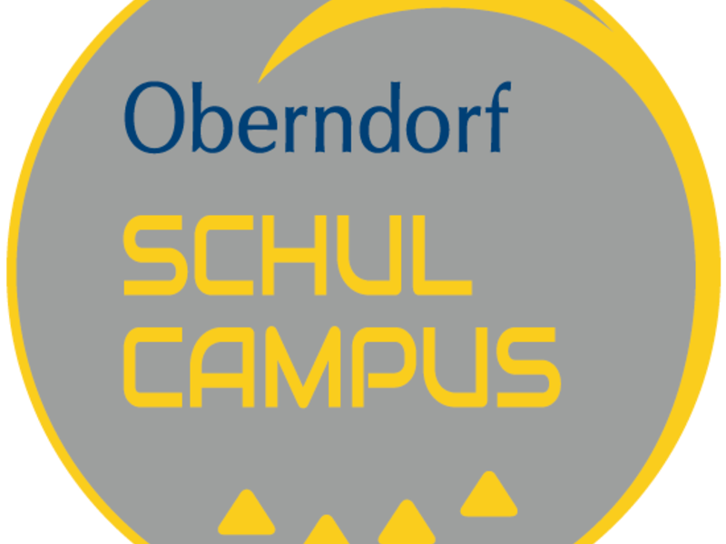 Ein graues rundes Logo mit der Aufschrift "Oberndorf SCHULCAMPUS", einem gelben Bogen und drei gelben Dreiecken am unteren Rand.